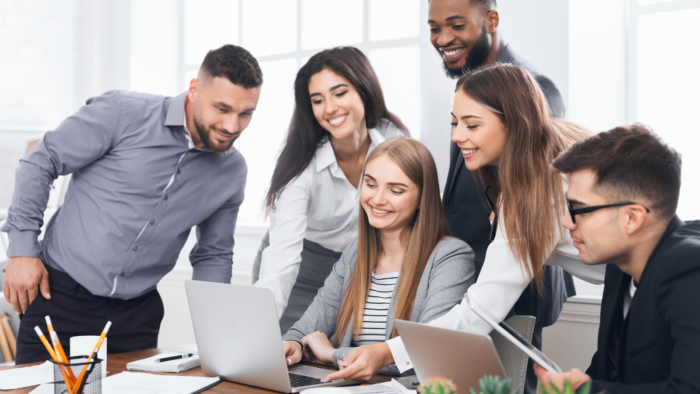 Diverse team of professionals collaborating around a laptop during a productive office meeting.