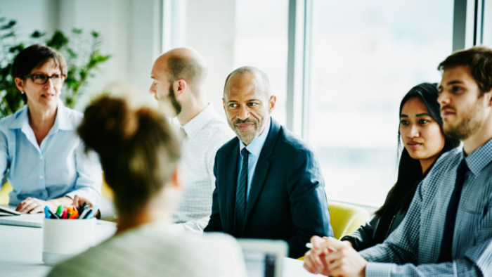 Business leader demonstrating emotional intelligence by actively engaging with team members during a collaborative workplace meeting.