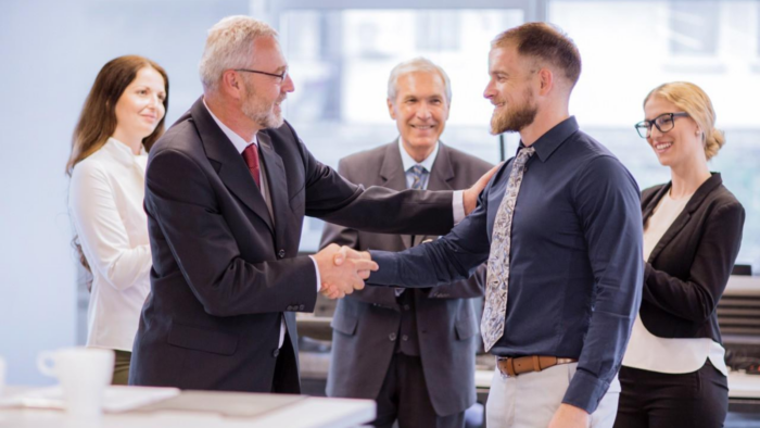 Professional employee receiving recognition and promotion from a senior manager in a corporate workplace