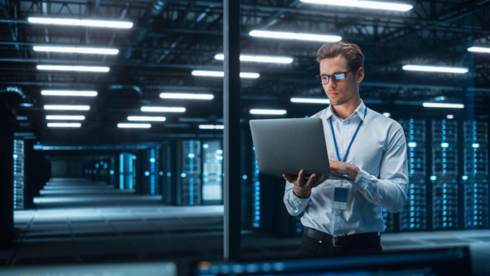 Data center professional working with a laptop in a modern server room