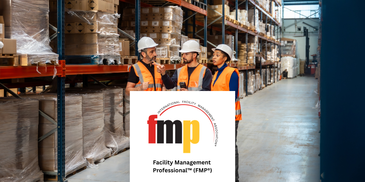 Warehouse facility management professionals wearing safety helmets and orange high-visibility vests discussing operations in a large storage warehouse, with the IFMA Facility Management Professional (FMP) certification logo displayed in the foreground.