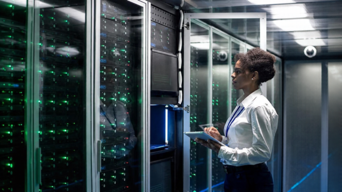 Data centre professional monitoring server racks with a tablet in a modern data centre.