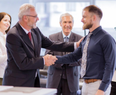 Professional employee receiving recognition and promotion from a senior manager in a corporate workplace