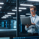 Data center professional working with a laptop in a modern server room