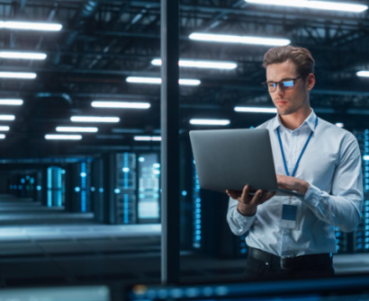 Data center professional working with a laptop in a modern server room
