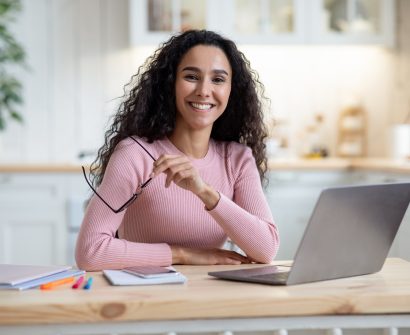 remote-entrepreneurship-happy-millennial-woman-sitting-at-table-with-laptop-in-kitchen