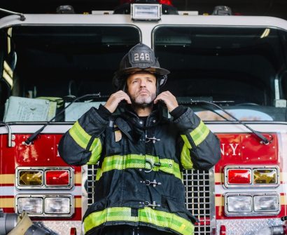 usa-new-york-portrait-of-firefighter-putting-on-helmet-in-front-of-fire-engine-e1706460494217.jpg